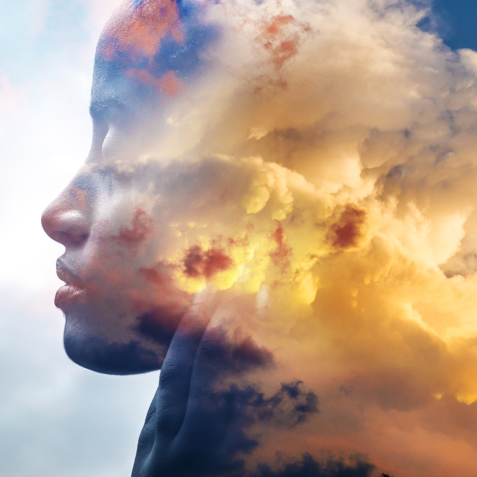 Doube exposed image of a woman's face and clouds backlit by the sun