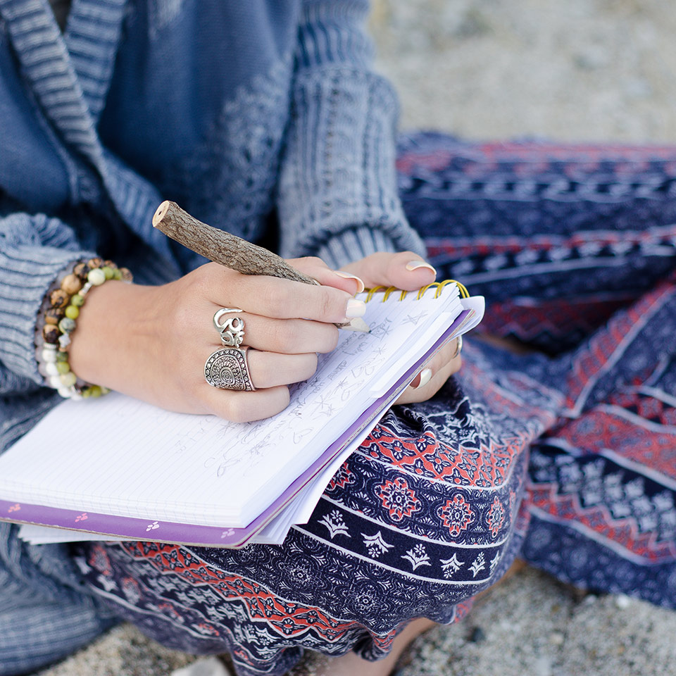 Woman sitting on a beach writing on a notebook